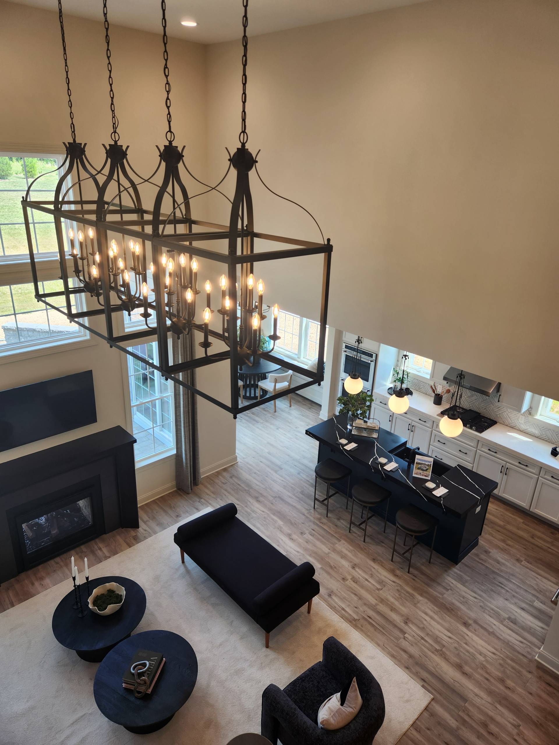 Open concept family room and kitchen with professionally installed statement chandelier and recessed lighting in a new Pennsylvania home.