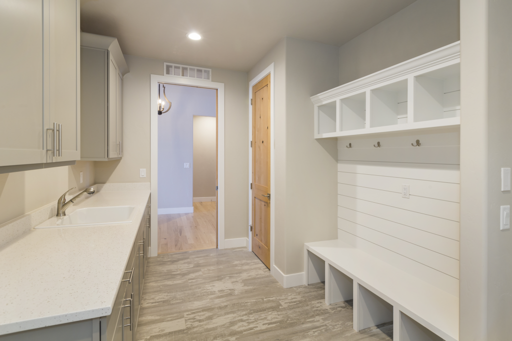 residential electrical company utility room with sink, cabinets, and built in white bench with cubbies and hooks